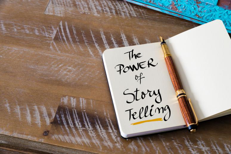 Retro effect and toned image of notebook next to a fountain pen. Business concept image with handwritten text THE POWER OF STORY TELLING