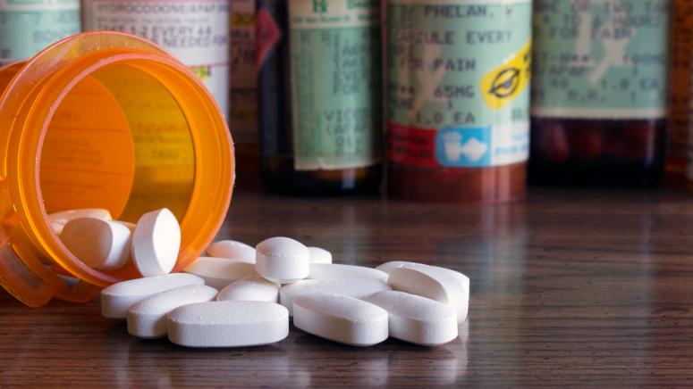 prescription pills spilling on a table with pill containters behind