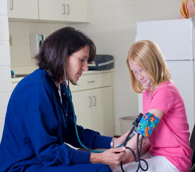 School nurse checking blood pressure of student patient